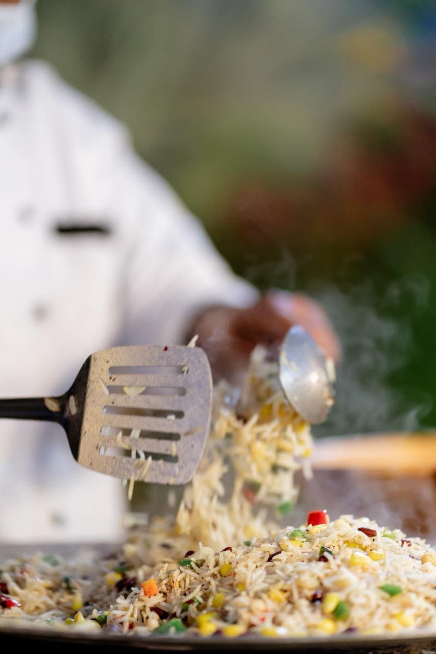 Chef plating a dish at a live catering counter