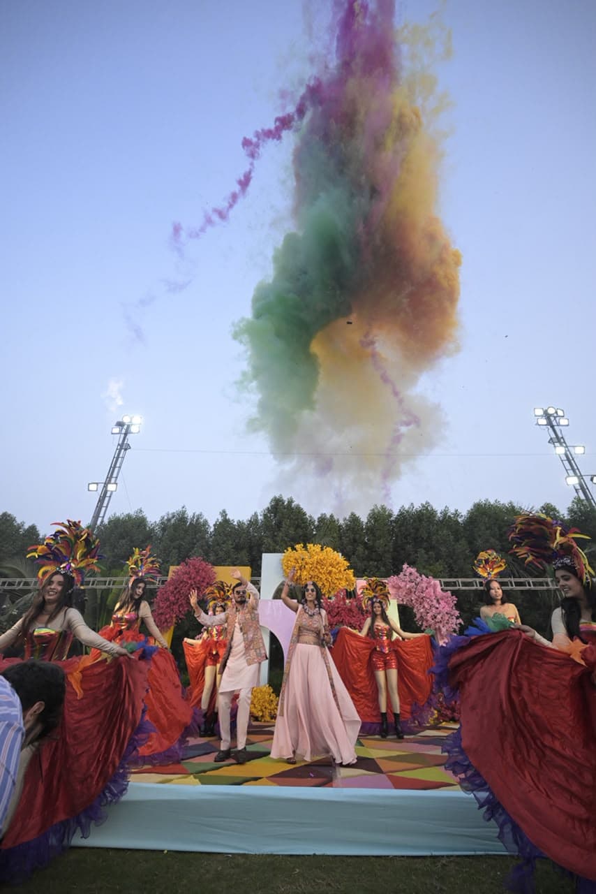 Couple celebrating with a colourful powder blast at their sangeet